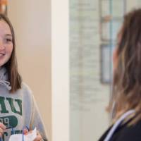 A student smiles while holding her gift bag